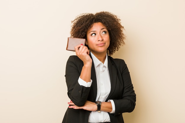 Jonge vrouw die een portefeuille houdt zijdelings kijkend met twijfelachtige en sceptische uitdrukking.