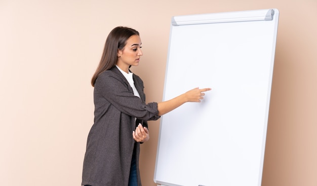 Jonge vrouw die een presentatie op wit bord geeft