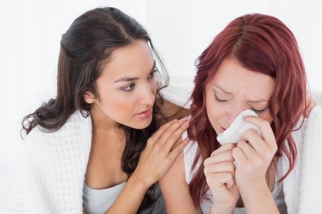 Jonge vrouw die een schreeuwende vrouwelijke vriend troost