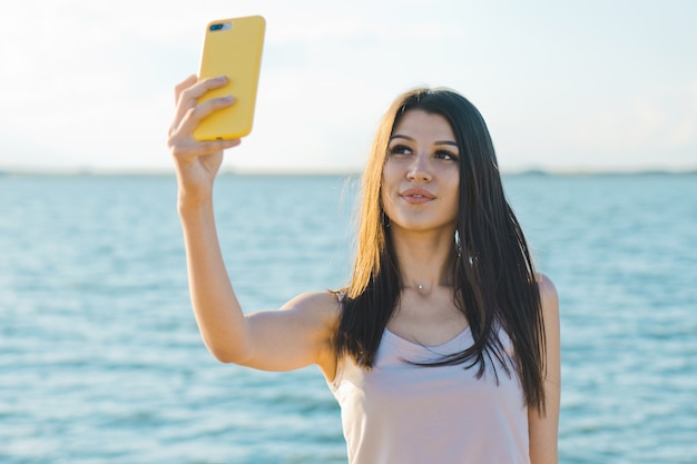 Jonge vrouw die een selfie neemt aan zee