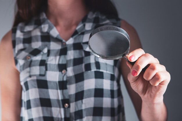 Jonge vrouw die een vergrootglas houdt