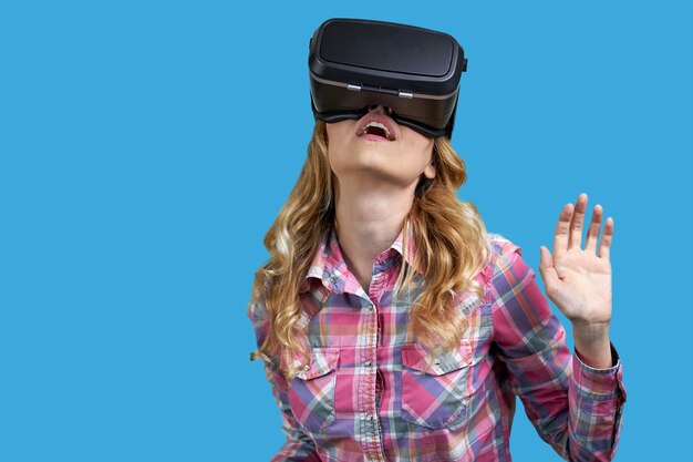 Jonge vrouw die een virtual reality-headset draagt op een onderdompeling in een achtergrond met kleur in de virtuele wereld