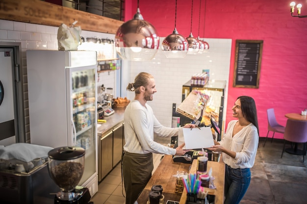 Jonge vrouw die een zak van een bakkerij steunt