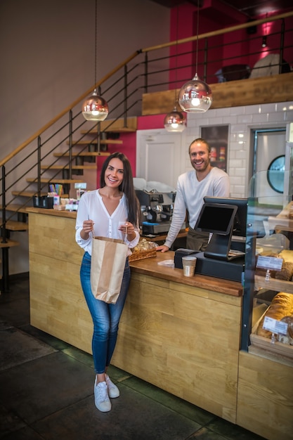 Jonge vrouw die een zak van een bakkerij steunt