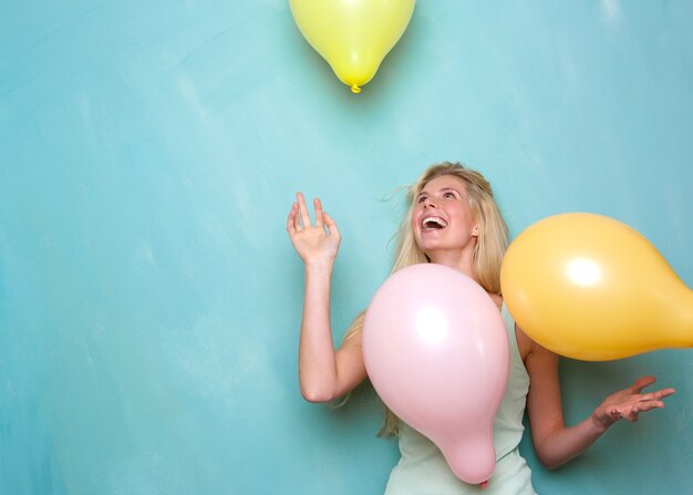 Jonge vrouw die en met ballons glimlacht speelt