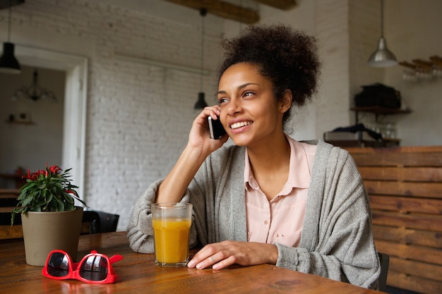 Jonge vrouw die en op mobiele telefoon glimlacht spreekt