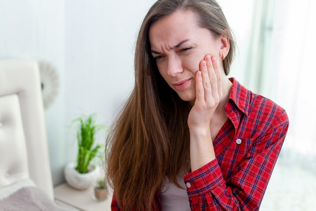 Jonge vrouw die en sterke pijnlijke tandpijn lijdt ervaart. Tandbederf en gevoeligheid