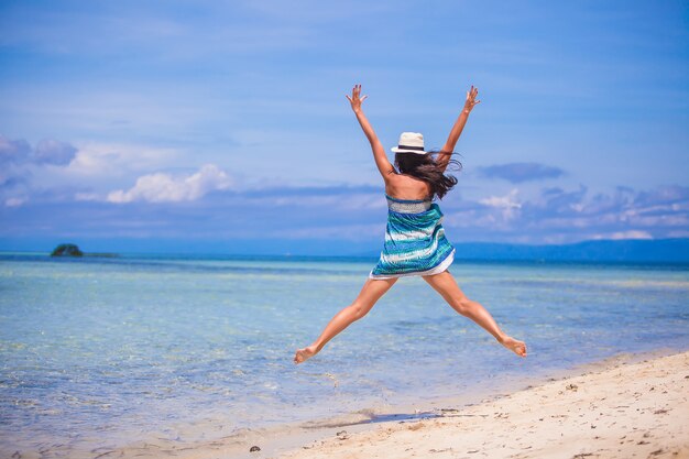 Jonge vrouw die en wapens omhoog op het strand springt opheft