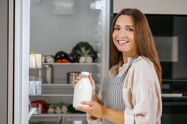 Jonge vrouw die eten uit de koelkast haalt