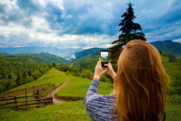 Jonge vrouw die foto's maakt van een geweldig mooi landschap met bergbos en wolkenlucht