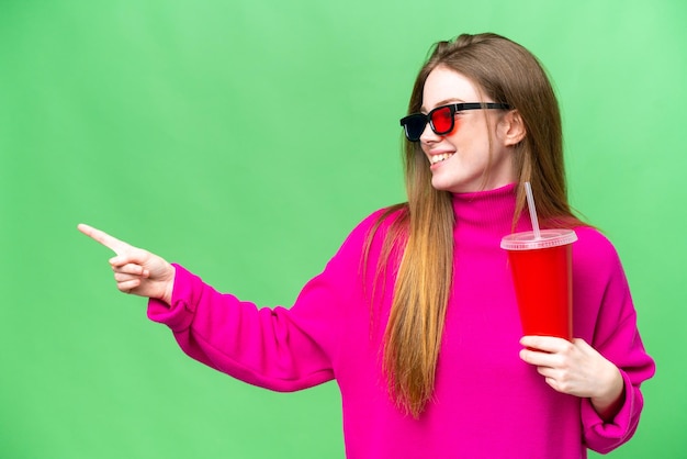 Jonge vrouw die frisdrank vasthoudt tijdens het kijken naar een 3D-film die naar de zijkant wijst om een product te presenteren