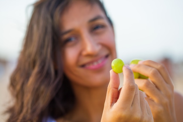 Jonge vrouw die fruit op het strand eet