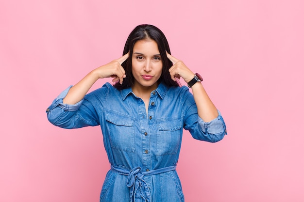 Jonge vrouw die geconcentreerd kijkt en hard nadenkt over een idee, zich een oplossing voor een uitdaging of probleem voorstelt