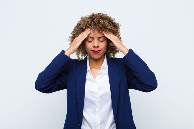 Jonge vrouw die geconcentreerd, nadenkend en geïnspireerd, brainstormend en met handen op voorhoofd over muur kijken kijken