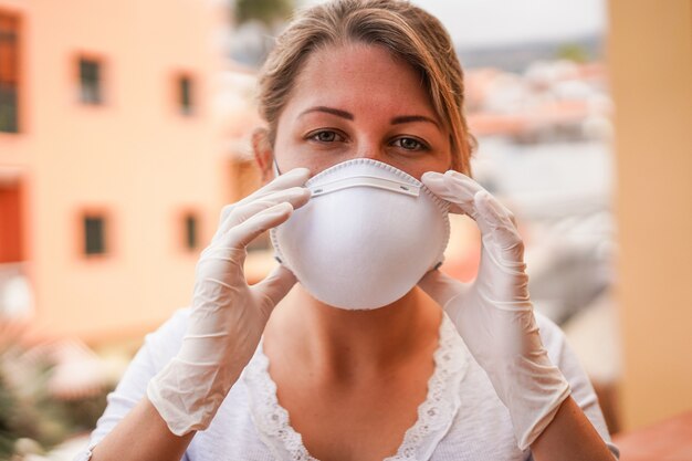 Jonge vrouw die gezichtsmasker en latexhandschoenen draagt voor coronaviruspreventie - houd op verspreidend concept Covid 19 - Nadruk op handen