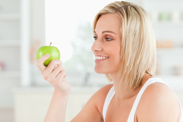 Jonge vrouw die groen een appel bekijkt