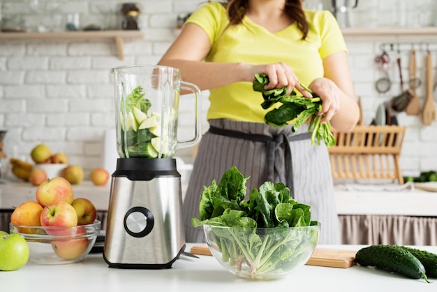 Jonge vrouw die groene spinaziesmoothie maakt thuis keuken