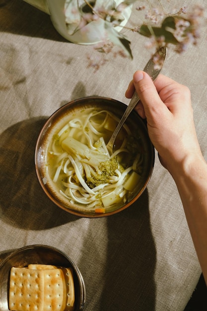 Jonge vrouw die groentesoep eet met broccoli en noedels