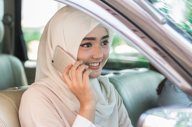 Jonge vrouw die haar auto drijven die mobiele telefoon met behulp van