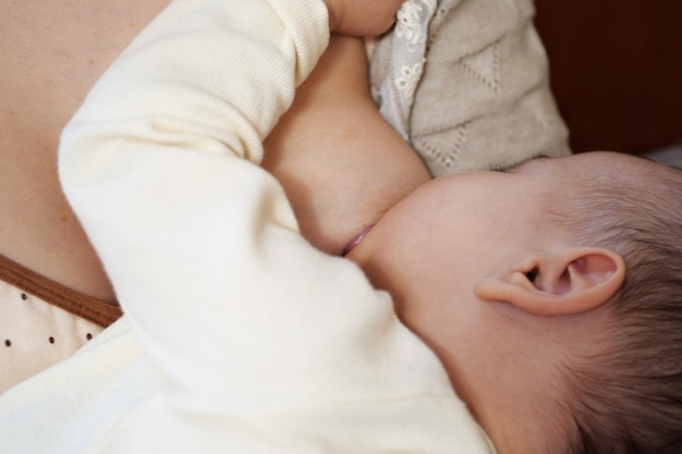 Jonge vrouw die haar baby thuis borstvoeding geeft