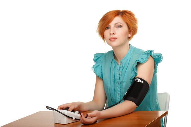 Jonge vrouw die haar druk met een geïsoleerde tonometer meet