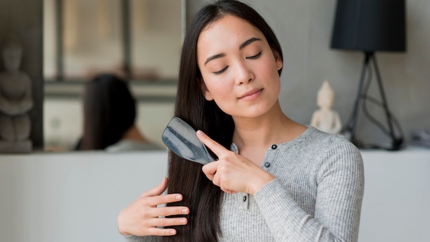 Foto jonge vrouw die haar haar borstelt