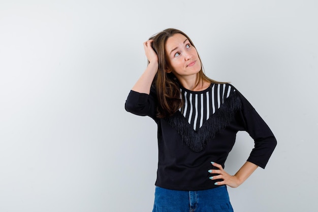 Jonge vrouw die haar hoofd op een witte achtergrond schraapt