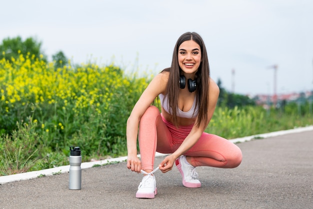 Jonge vrouw die haar kant bindt vóór een looppas. hardloper die haar schoenen vastbindt om zich voor te bereiden op hardlopen buiten