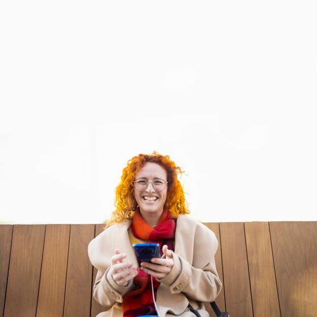 Jonge vrouw die haar smartphone gebruikt op een slimme bank in een moderne stad