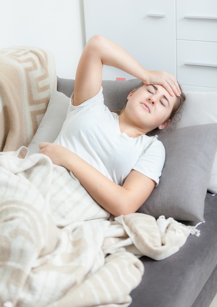 Jonge vrouw die haar temperatuur in bed opneemt en hoofdpijn heeft