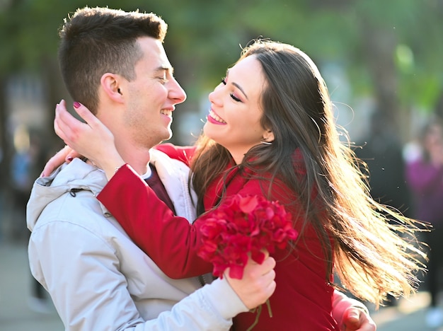 Jonge vrouw die haar vriend koestert omdat hij haar bloemen gaf - de Dagconcept van Valentine