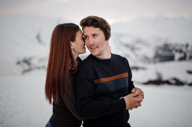 Jonge vrouw die haar vriend van terug op sneeuwberg omhelst