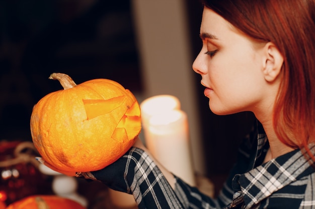 Jonge vrouw die Halloween-pompoen Jack-o-lantern maakt. Vrouwelijke handen snijden pompoenen met mes.