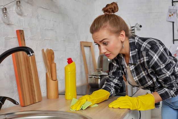 Jonge vrouw die handmatig, met de hand wast, met gele rubberen reinigingshandschoenen.