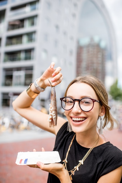 Jonge vrouw die haring eet met uien traditionele Nederlandse snack in de buurt van de Rotterdamse markt