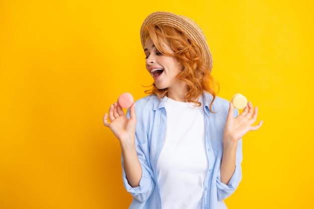 Jonge vrouw die heerlijke macaron op gele achtergrond eet Meisje eet de macaron