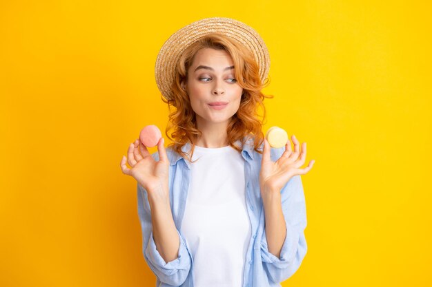 Jonge vrouw die heerlijke macaron op gele achtergrond eet Meisje eet de macaron