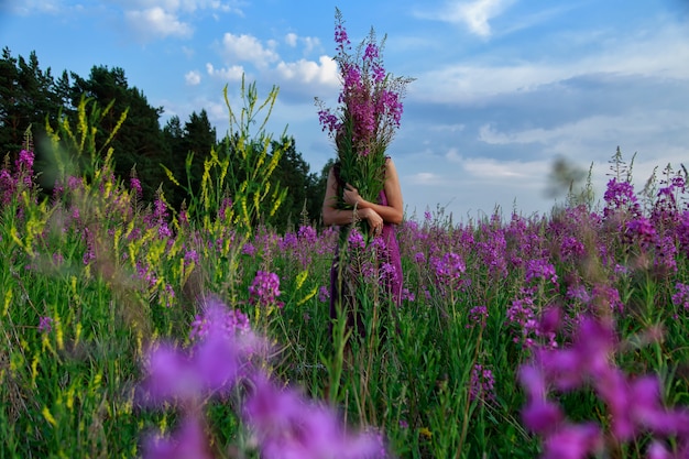 Jonge vrouw die het boeket van roze bloemen houdt.