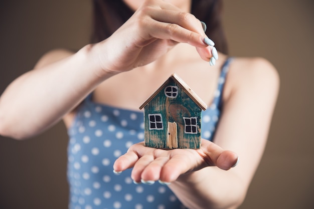 Jonge vrouw die het huis in handen beschermt