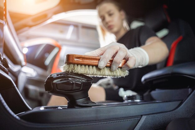 Jonge vrouw die het stuur van de auto schoonmaakt met een speciale borstel met schuim