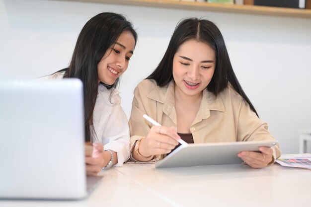 Jonge vrouw die ideeën of het opstarten van een businessplan deelt met haar collega terwijl ze samen in kantoor zit.