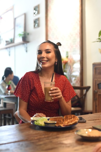 Jonge vrouw die ijskoffie drinkt in een coffeeshop