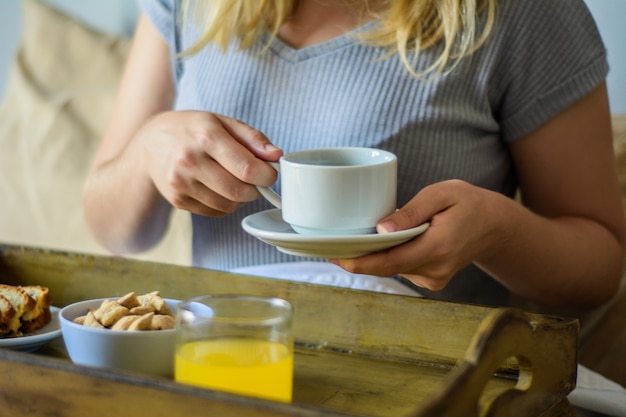 Jonge vrouw die in bed ontbijt eet