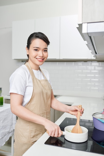 Jonge vrouw die in de keuken kookt