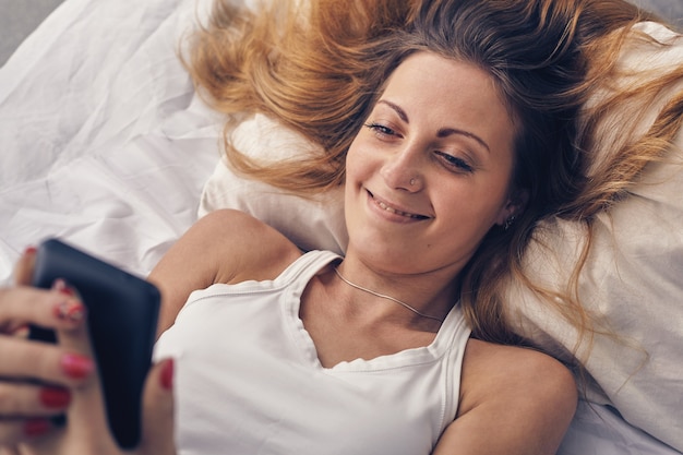 Jonge vrouw die in de ochtend slecht naar haar telefoon kijkt