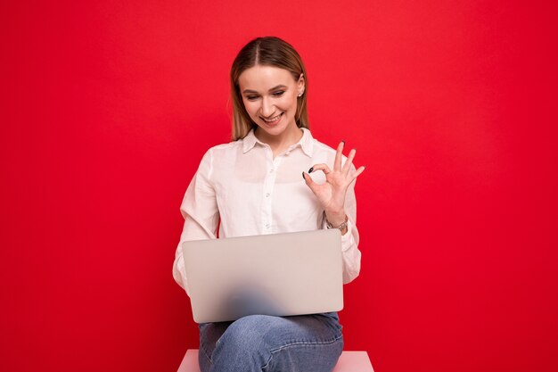 Jonge vrouw die in een wit overhemd een videogesprek voert vanaf laptop
