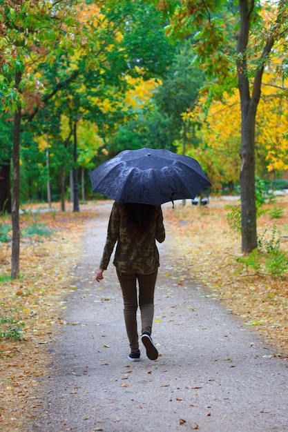Jonge vrouw die in het bos loopt met een paraplu