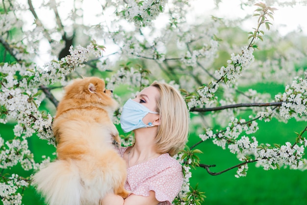 Jonge vrouw die in medisch masker een hond houdt