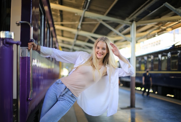 Jonge vrouw die in vintage trein wacht, ontspannen en zorgeloos op het perron