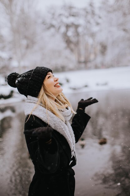 Jonge vrouw die in warme kleren in sneeuw geniet